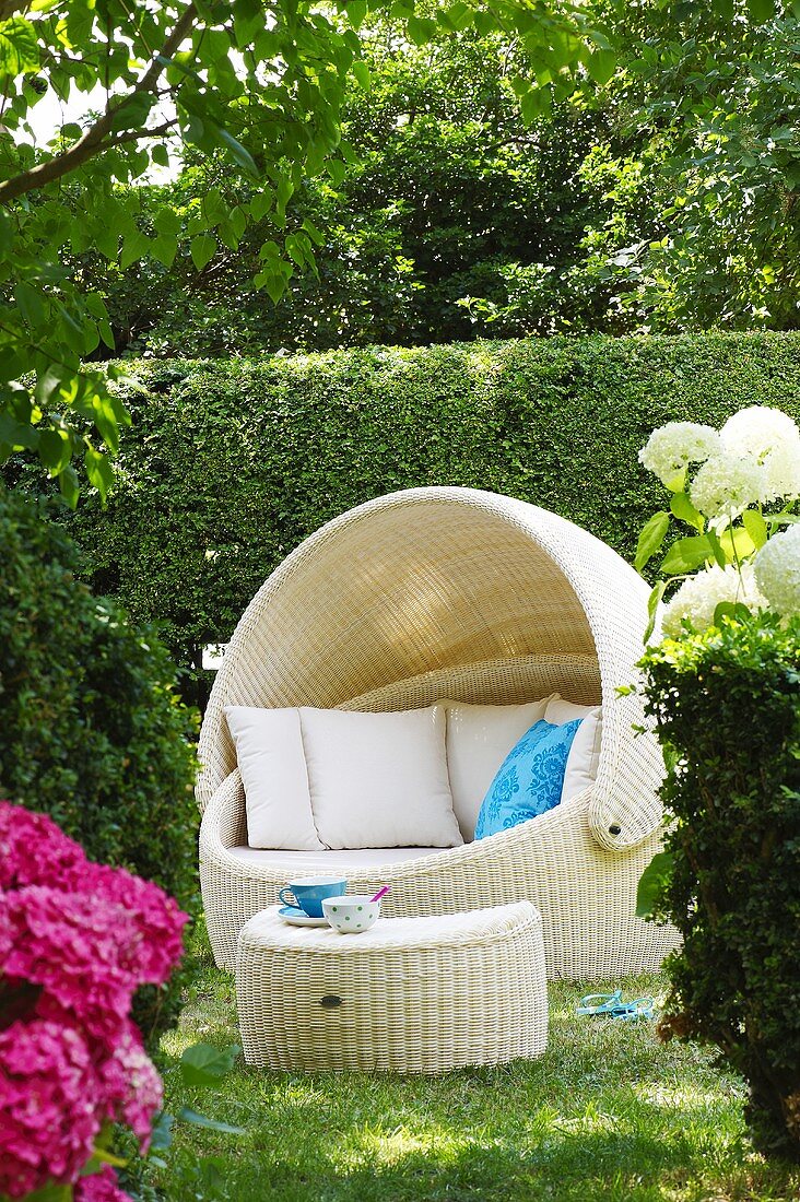 A luxurious roofed wicker beach chair with a side table in a garden