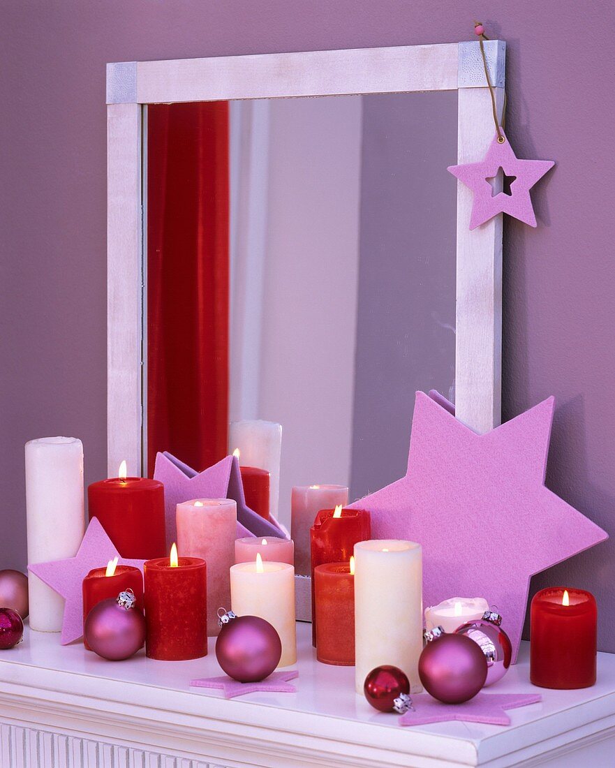 Stars, Christmas baubles and candles in front of a mirror