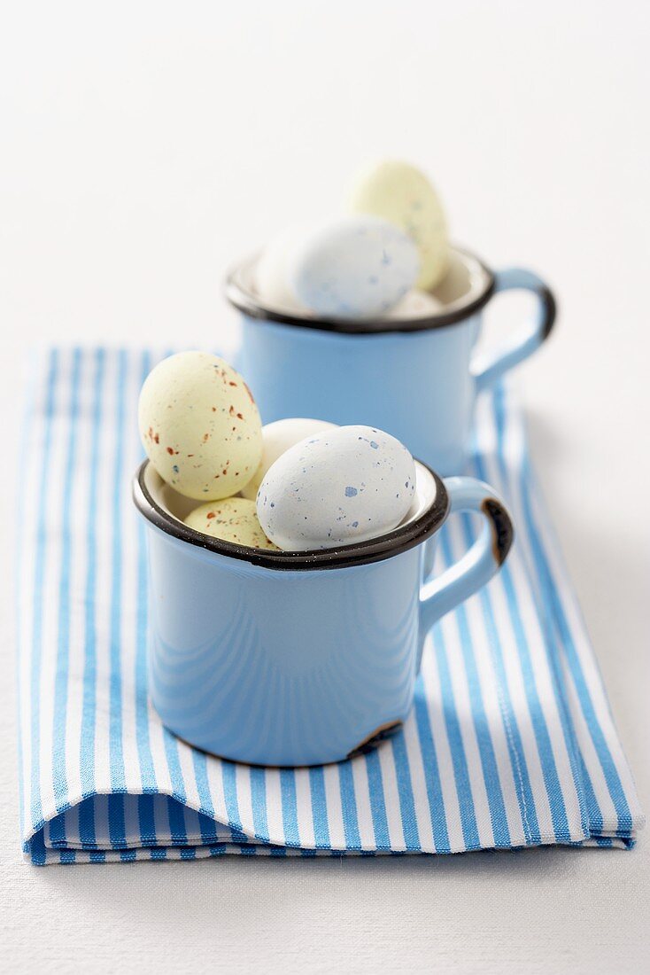 Coloured quails' eggs for Easter in two enamel cups