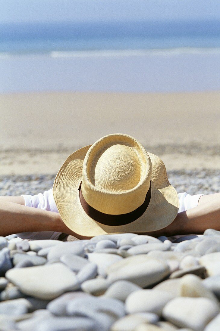 Mann mit Hut liegt am Strand