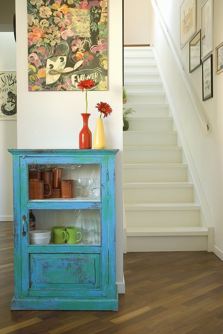 A blue cabinet and a flight of white, wooden stairs