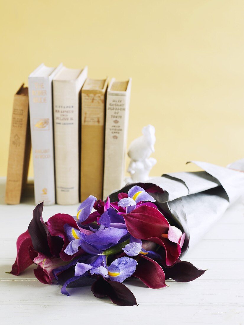 Blumenstrauss mit Schwertlilien vor Büchern