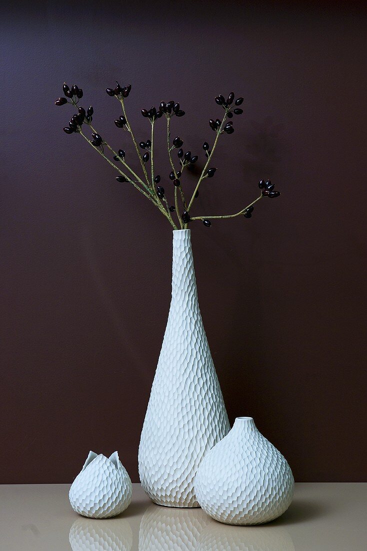 Three vases, branches with berries in one of them