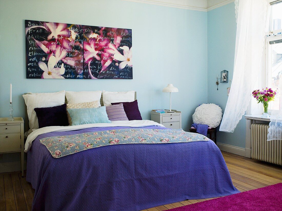 Schlafzimmer mit modernem Blumenbild über Doppelbett mit Tagesdecke & Zierkissen