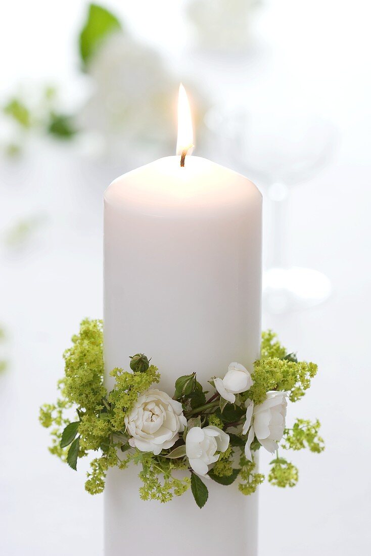 weiße Kerze mit Kränzchen aus Frauenmantel und weissen Rosen