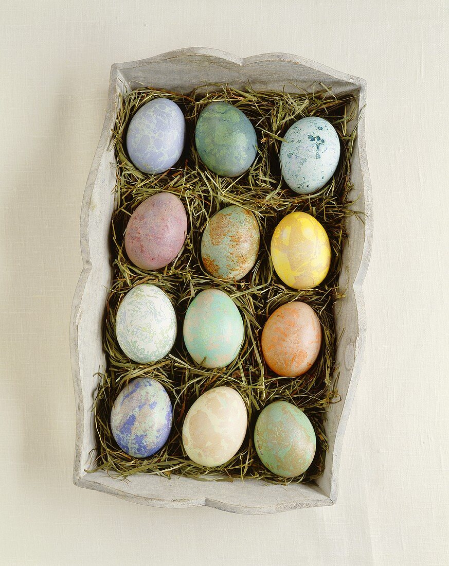 Marbled Easter eggs in wooden box with straw