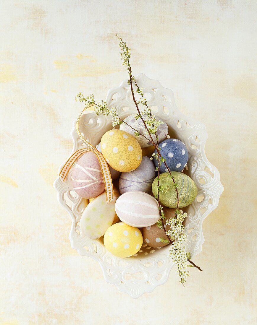 Coloured Easter eggs with flowering twigs in a dish