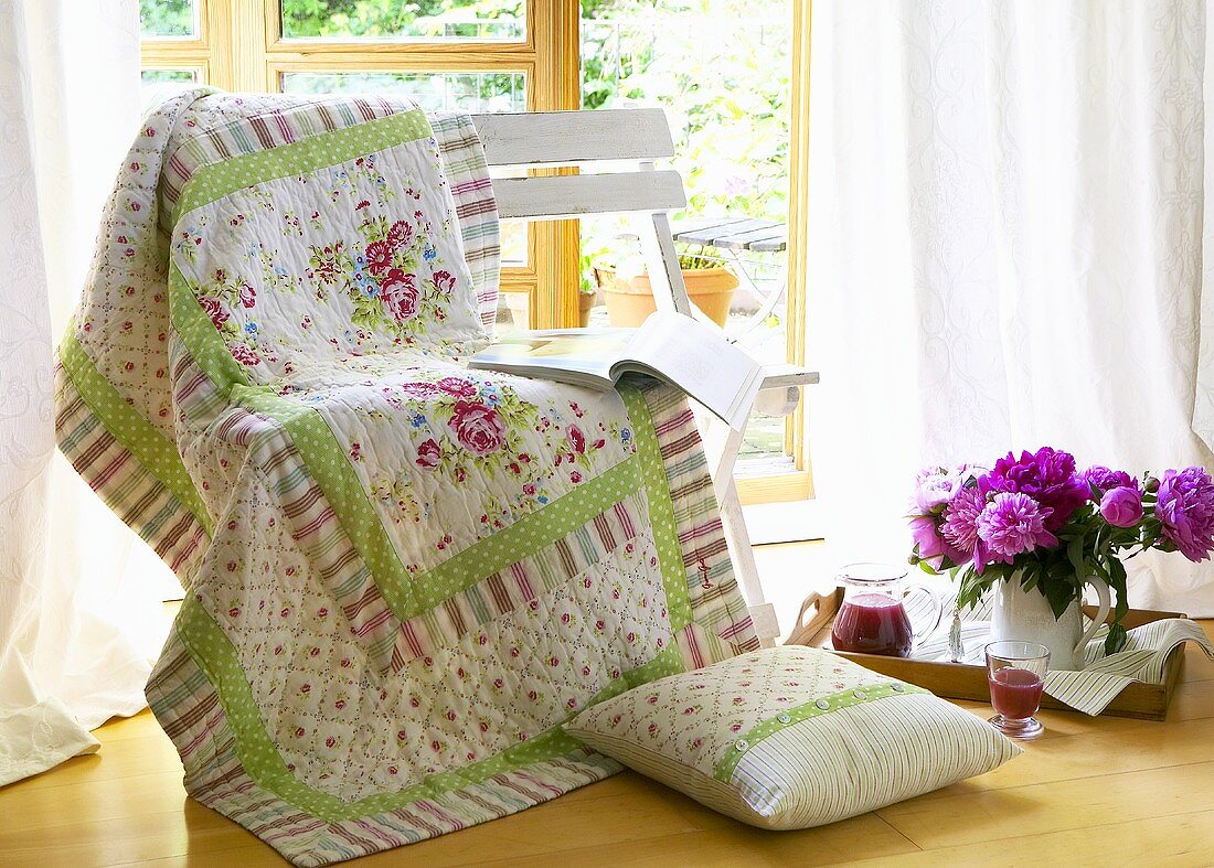 Bedspread and book on bench, peonies and juice on tray
