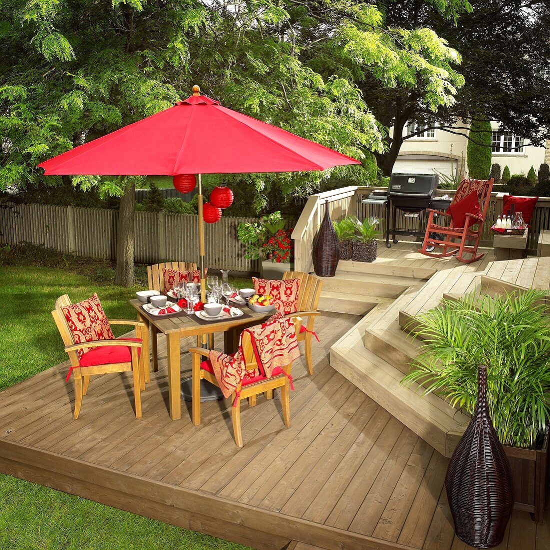 Gedeckter Tisch mit rotem Sonnenschirm auf Holz-Terrasse