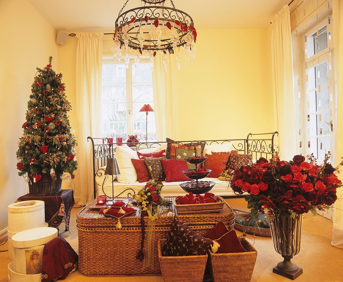 Weihnachtlich dekoriertes Wohnzimmer mit Metallsofa, Weihnachtsbaum, Körben, Schachteln & Blumenschmuck