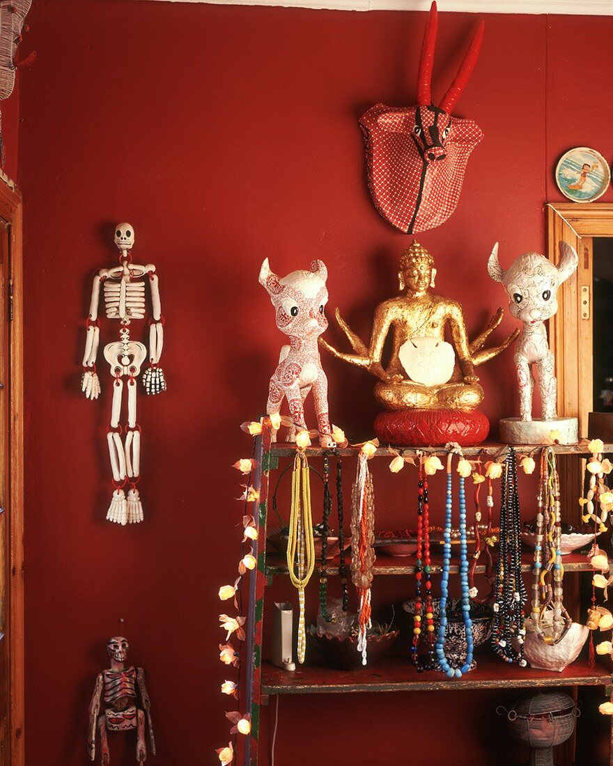 Halsketten, Buddha-Figur, Deko-Figuren & Deko-Sklette auf Regal & an roter Wand hängend