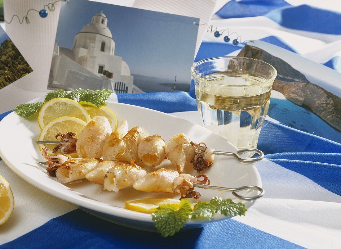 Tintenfischspiesse, Weißwein und griechische Tischdekoration