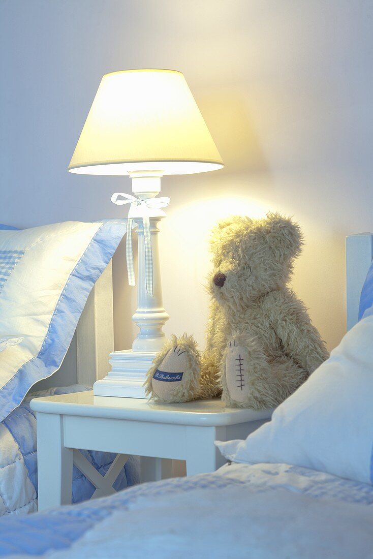 Schlafzimmer mit Teddybär & Tischleuchte auf Nachttischchen