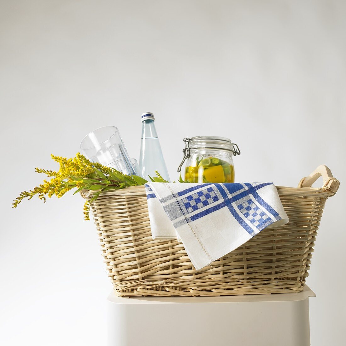 Pickled vegetables, flowers and a bottle of water in a basket