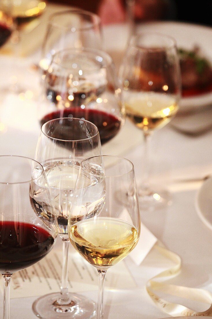 Gläser mit Rotwein, Weißwein und Wasser auf gedecktem Tisch