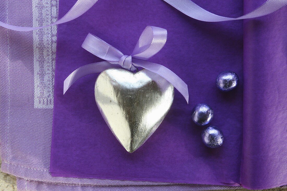 Silver heart with a bow on a purple surface