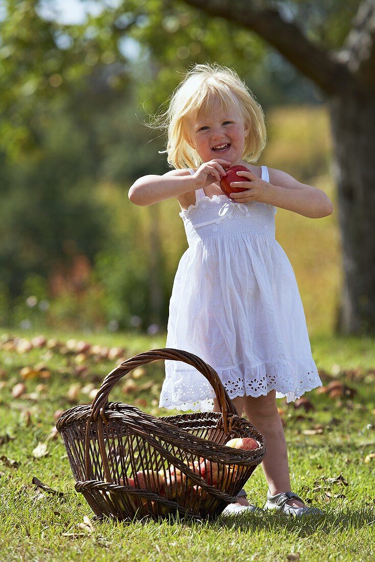 Blondes Mädchen mit Apfel im Garten