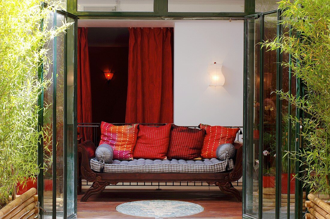 Sofa with cushions in front of opened terrace door