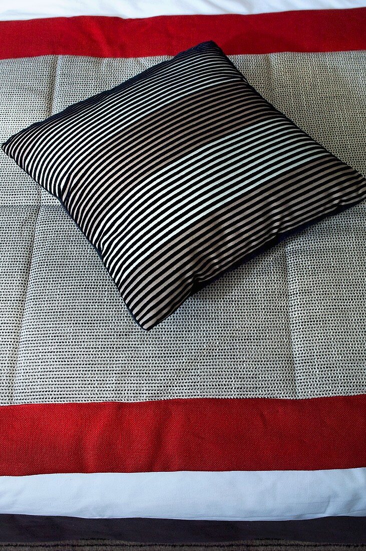 Striped cushion on a bedspread