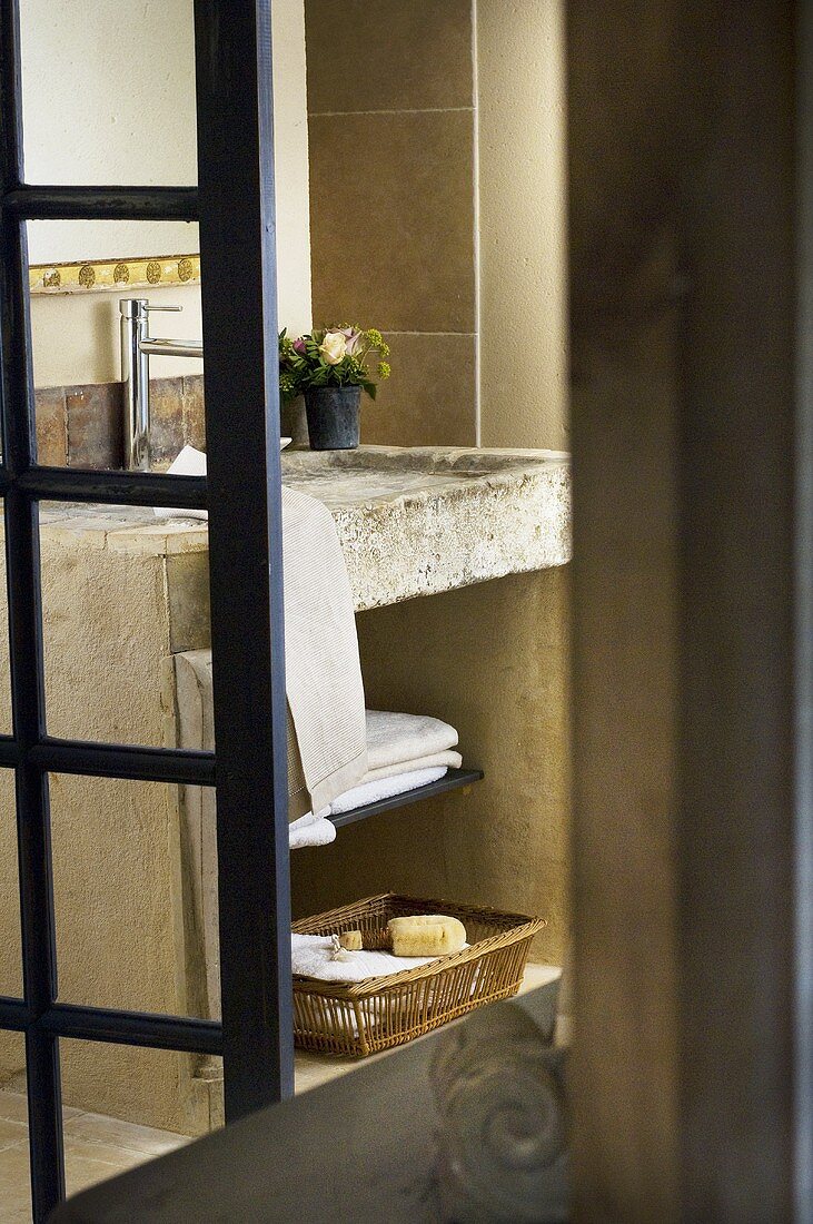 Blick durch geöffenete Glastür auf gemauertes Waschbecken mit Handtüchern