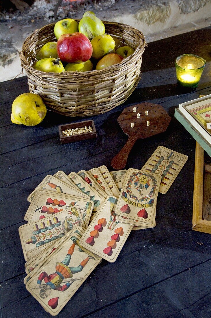 Kartenspiel und Korb mit Äpfeln & Quitten auf einem Tisch