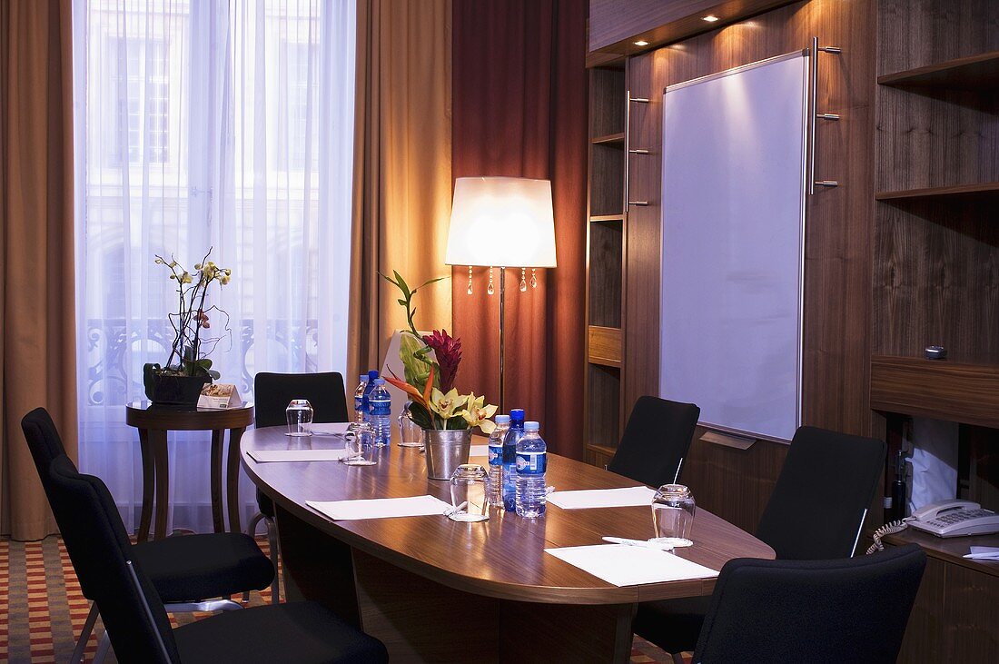 Beleuchteter Seminarraum in einem Hotel (Paris, Frankreich) mit Konferenztisch & Wandtafel