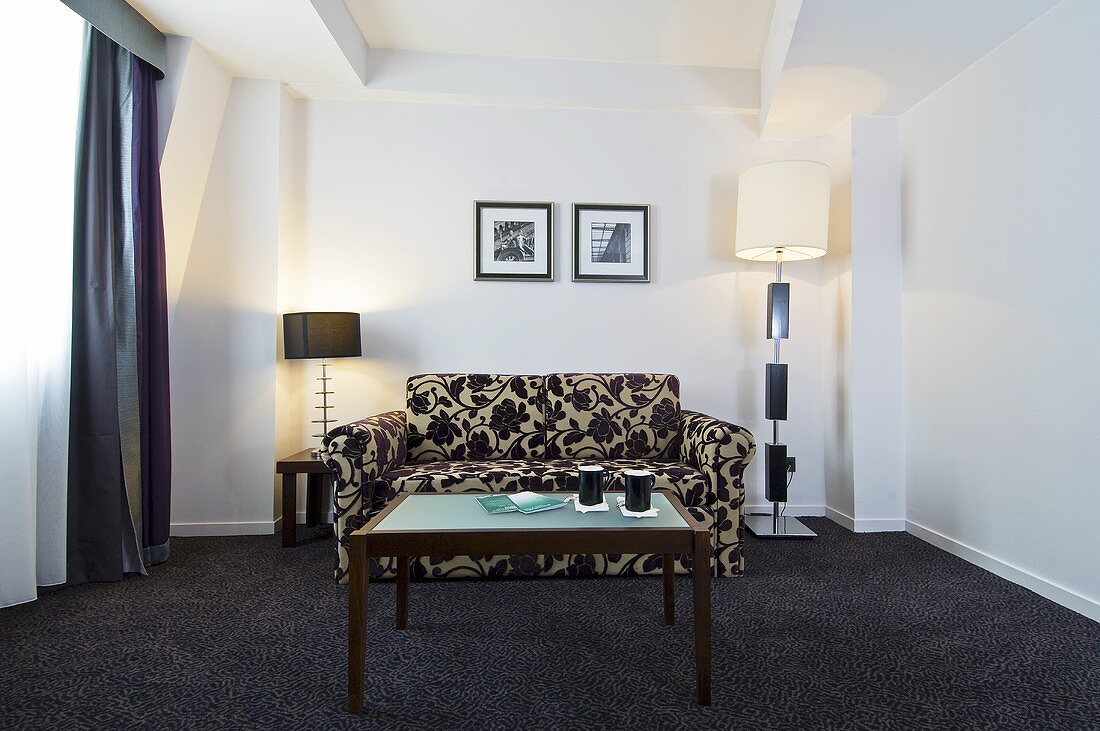 Sitzecke mit Sofa, Couchtisch & Leuchten in stilvollem Hotelzimmer (Paris, Frankreich)