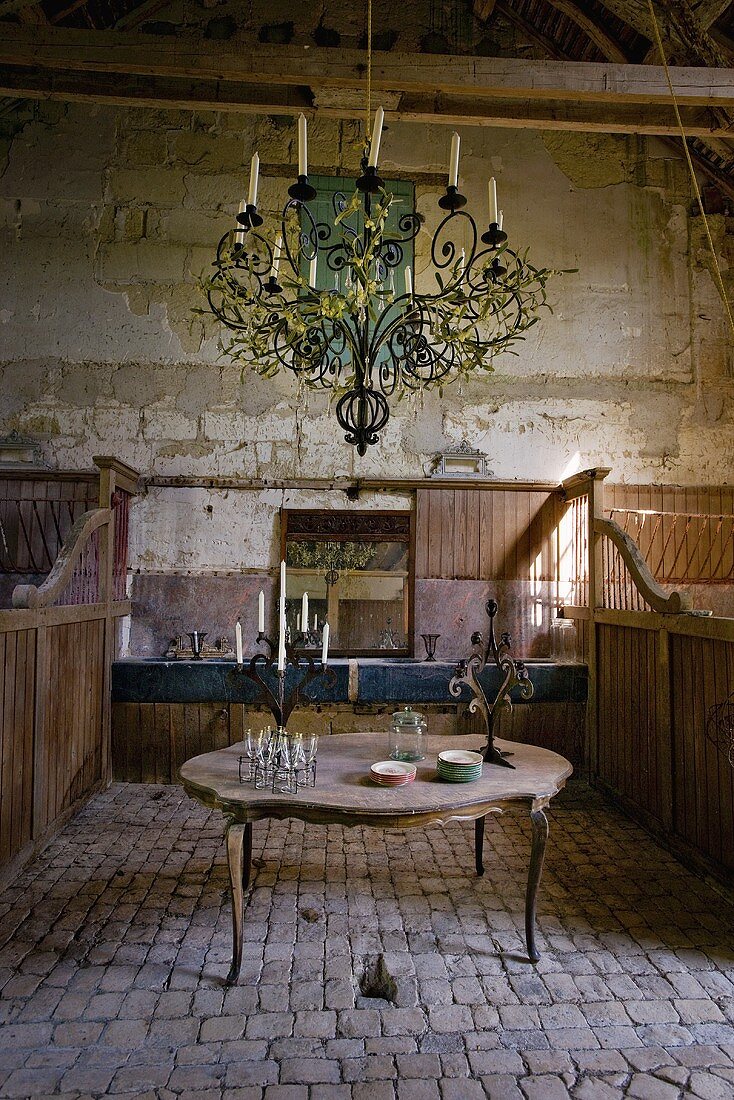 Rustikaler Innenraum mit Tisch & Kerzen-Kronleuchter im Schloss La Verrerie (Frankreich)