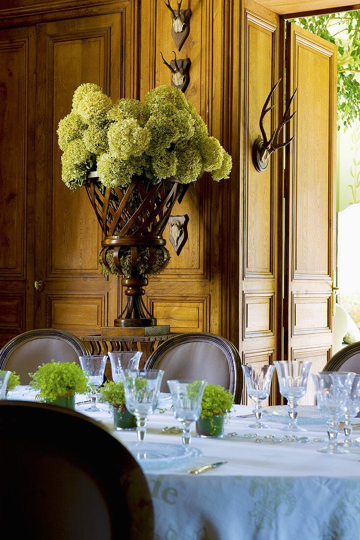 Gedeckter Tisch, Blumenschmuck & Tiergeweihe als Wanddeko im Speisesaal des Schlosses La Verrerie (Frankreich)