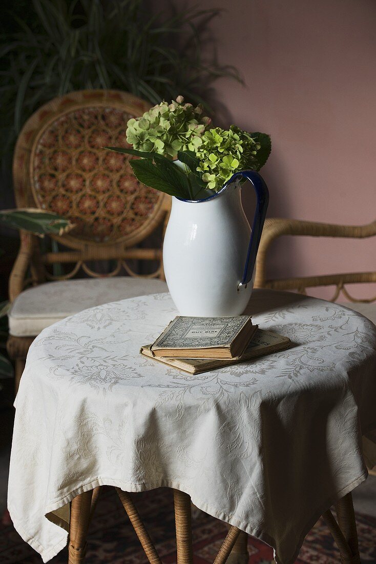 Hydrangeas in jug and books on table