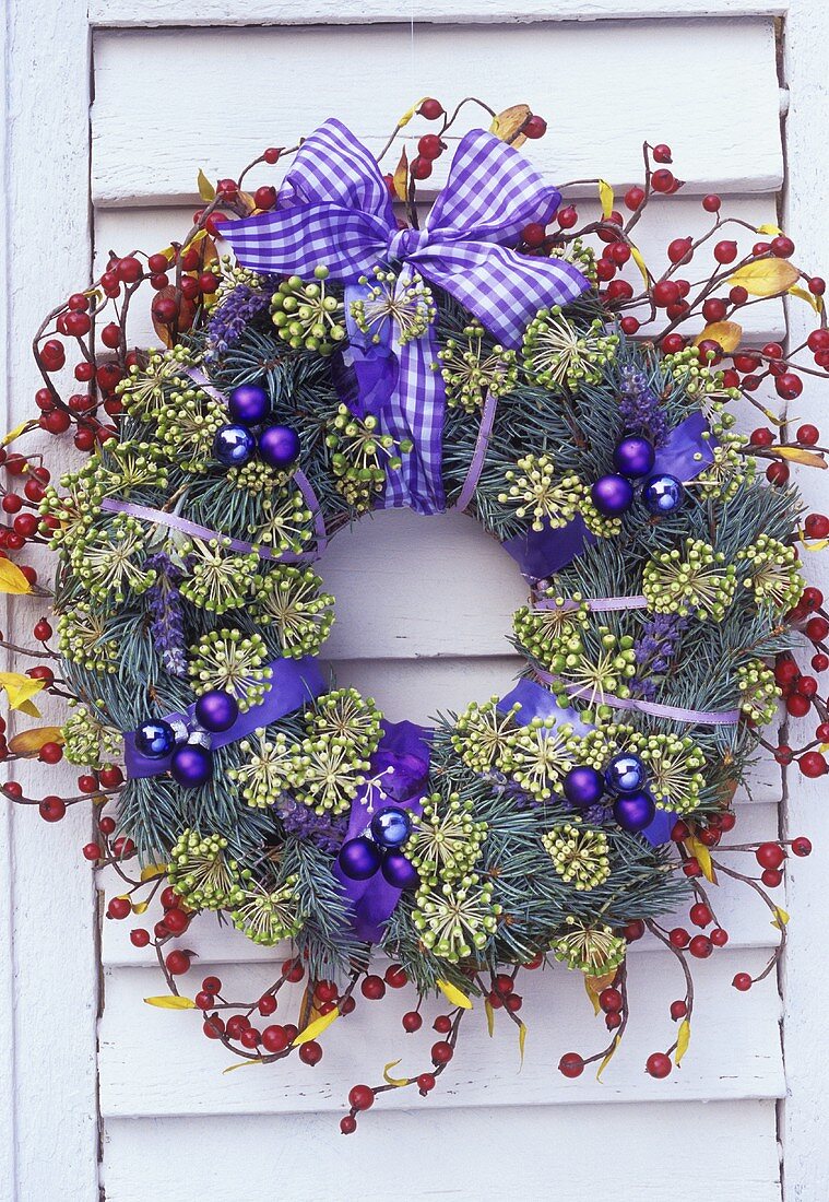 Christmas wreath with purple decorations on white shutter