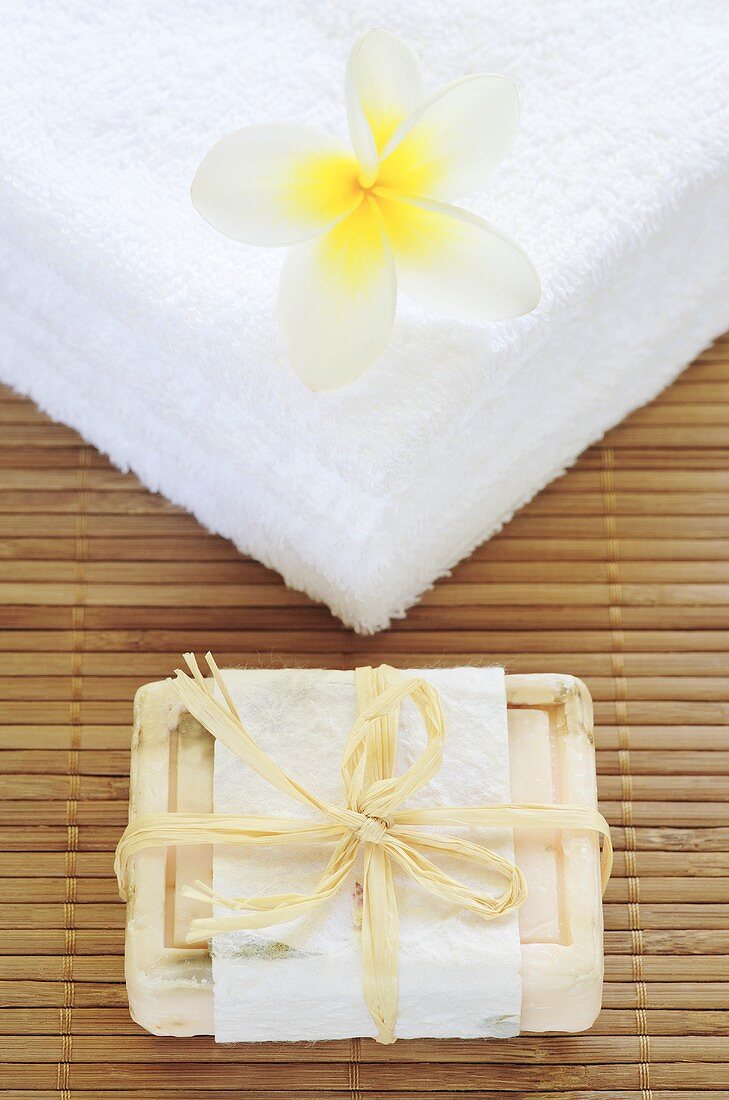 Frangipani flower on towels and a bar of olive soap