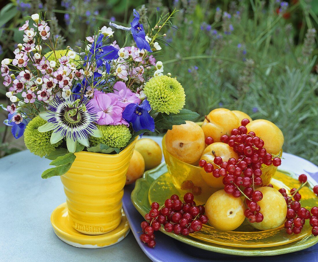 Yellow plums, redcurrants and vase of flowers