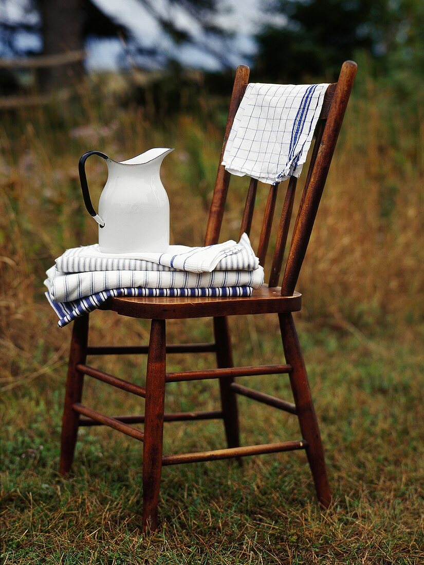 Holzstuhl mit Handtüchern und einem Krug Wasser im Freien