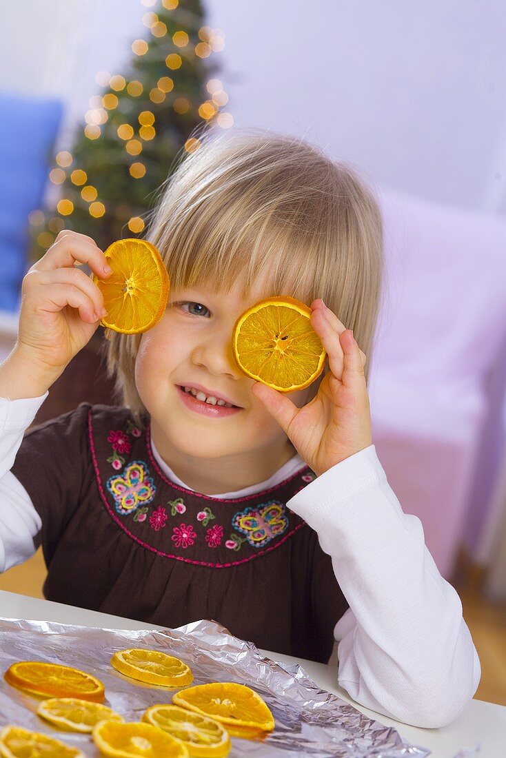 Kleines Mädchen mit getrockneten Orangenscheiben