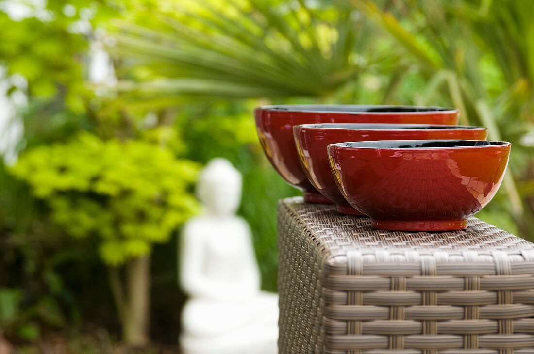 Three red painted bowls from the Burma in an oriental garden