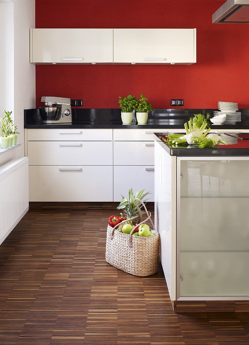 Einkaufstasche in moderner Küche mit weissen Schränken & rot gestrichenen Wänden