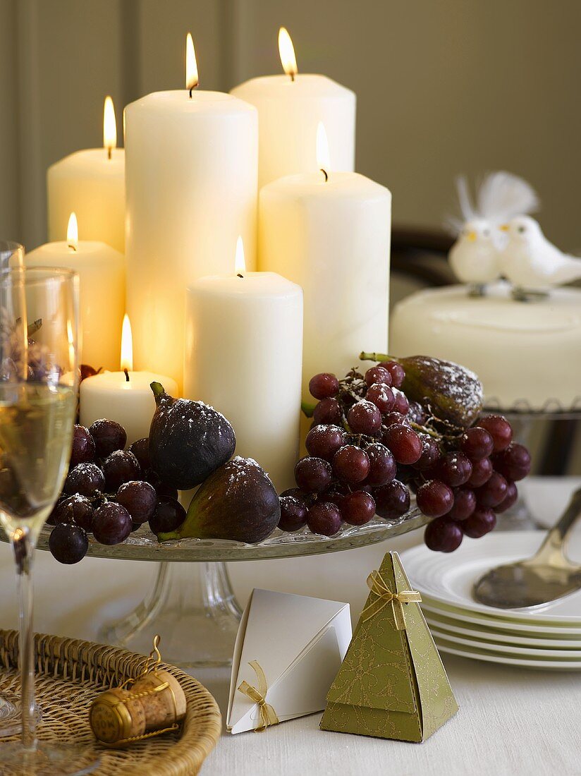 Christmas table decoration with candles, grapes and figs