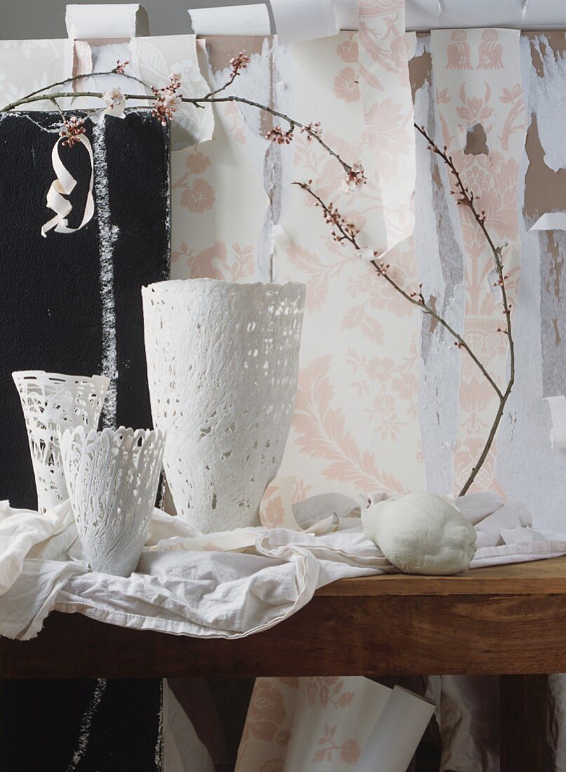 weiße Vasen und Frühlingszweige vor abgerissener Tapete