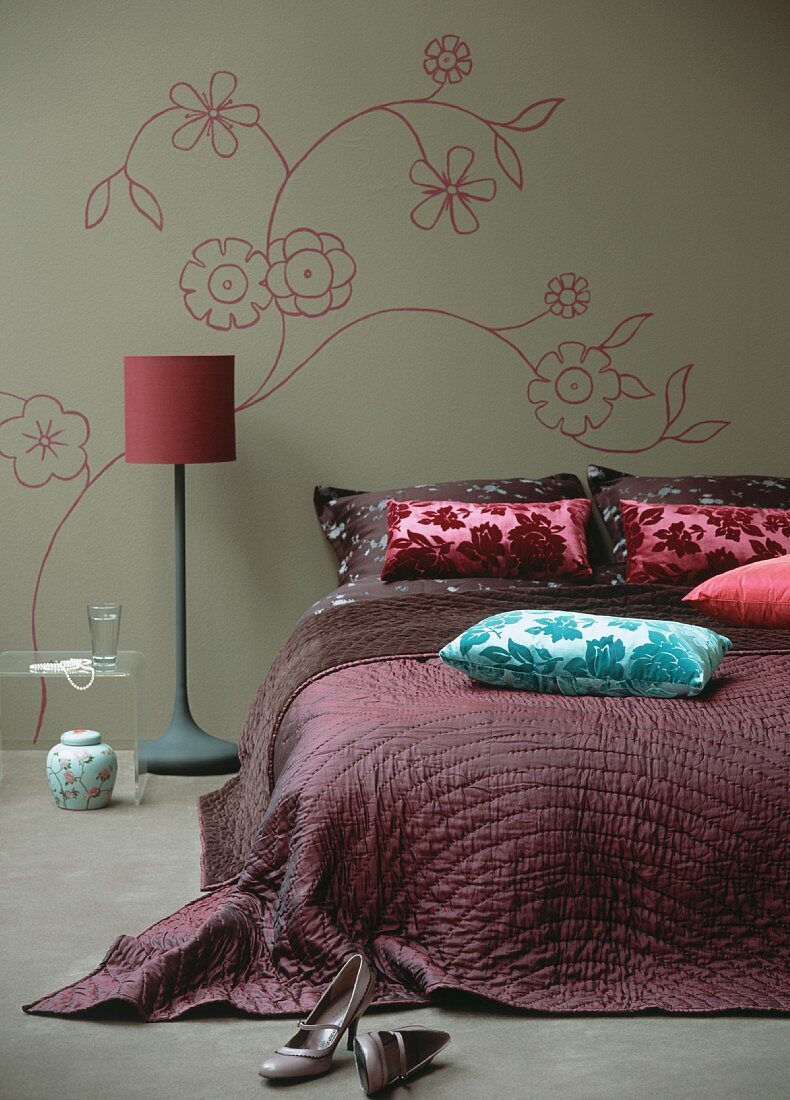 Schlafzimmer in Lila & Grau mit Doppelbett, Stepdecke, Samtkissen, Stehlampe & Blumenmotiv an der Zimmerwand