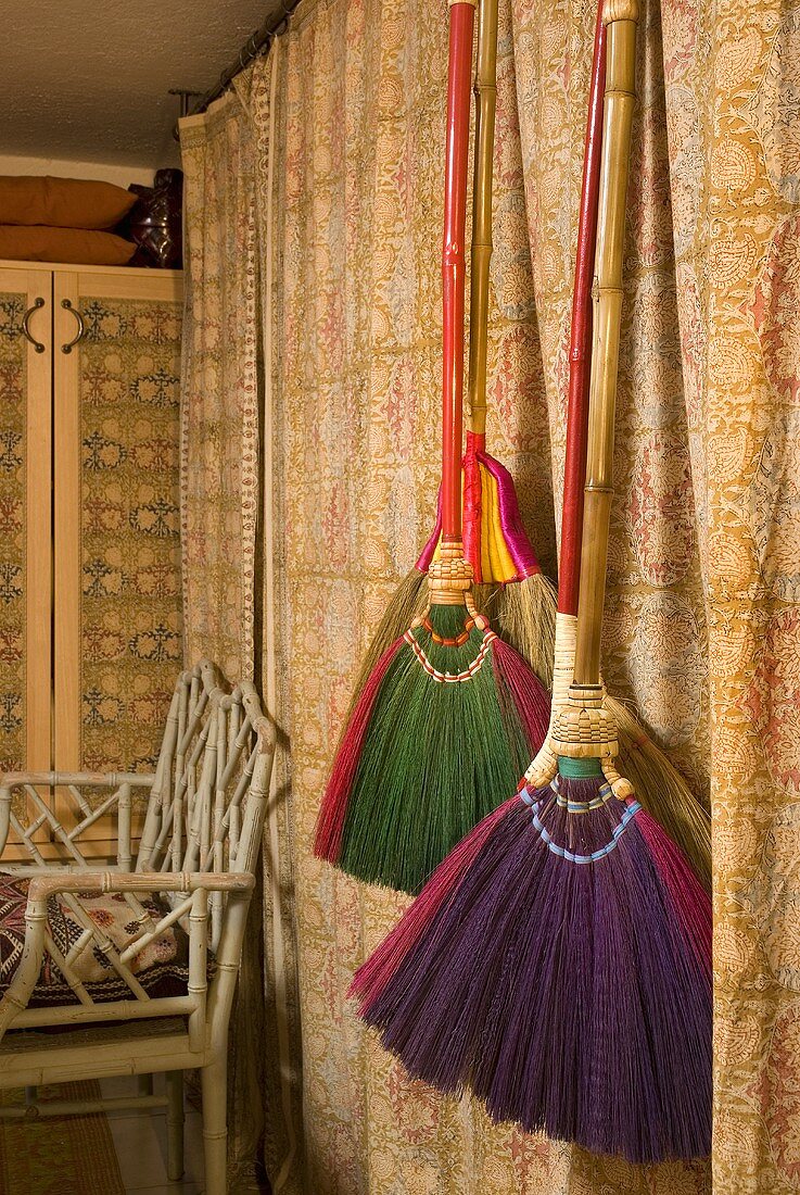 Colorful brooms hanging in front of a curtain