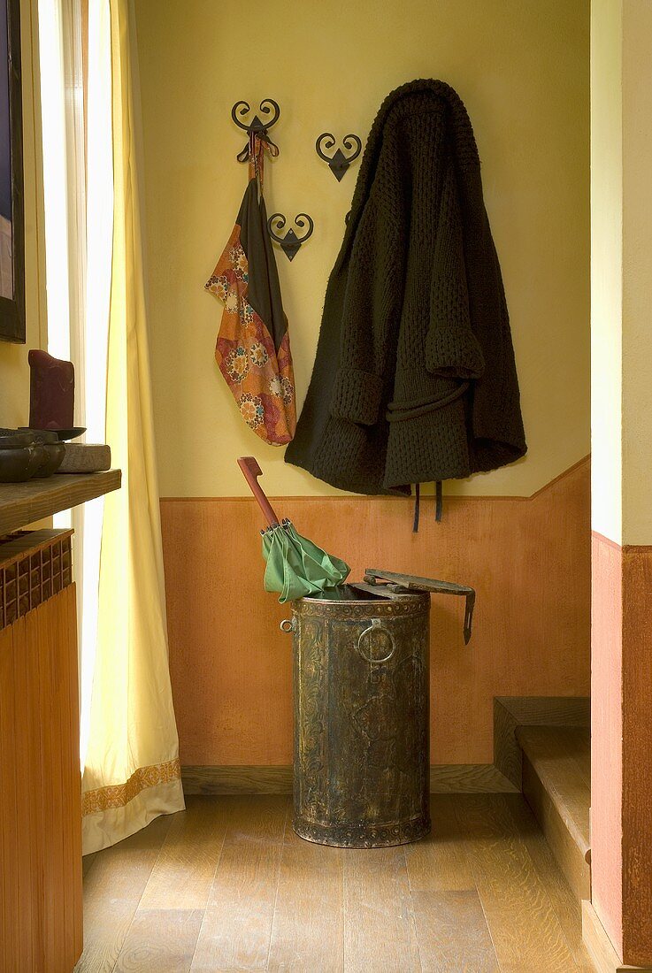 Umbrella rack and wardrobe in front of a wall painted yellow and orange