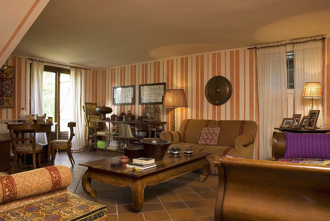 Rustikaler Couchtisch und Sofa vor Tapete mit orange weißem Streifenmuster im Wohnraum