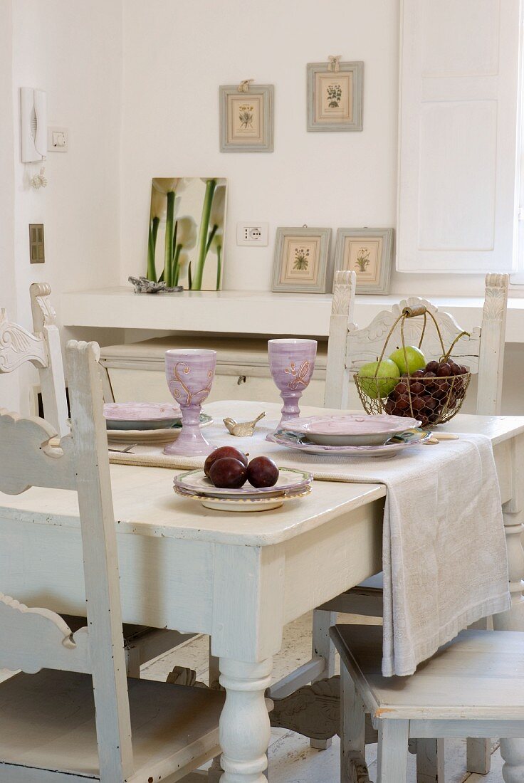 Gedeckter Tisch aus weiss lackiertem Holz mit Weingläsern aus Keramik