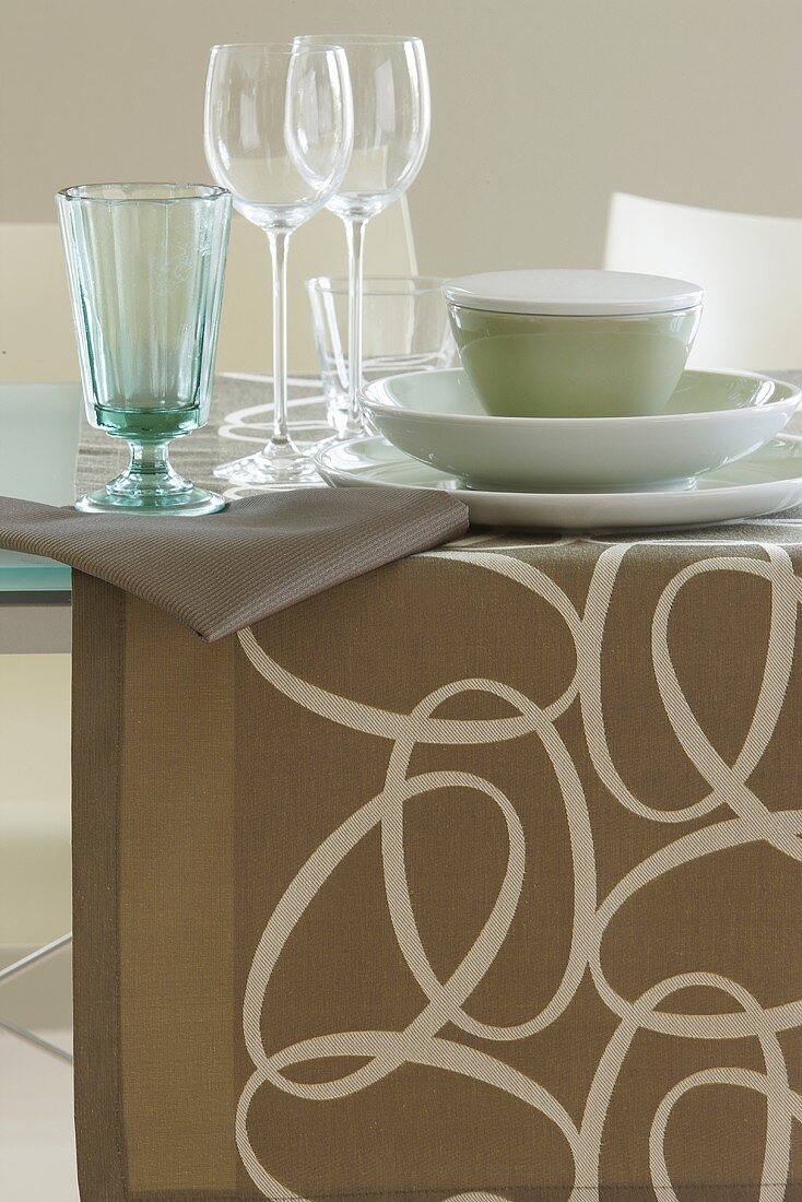 A dining table with a table runner and glasses