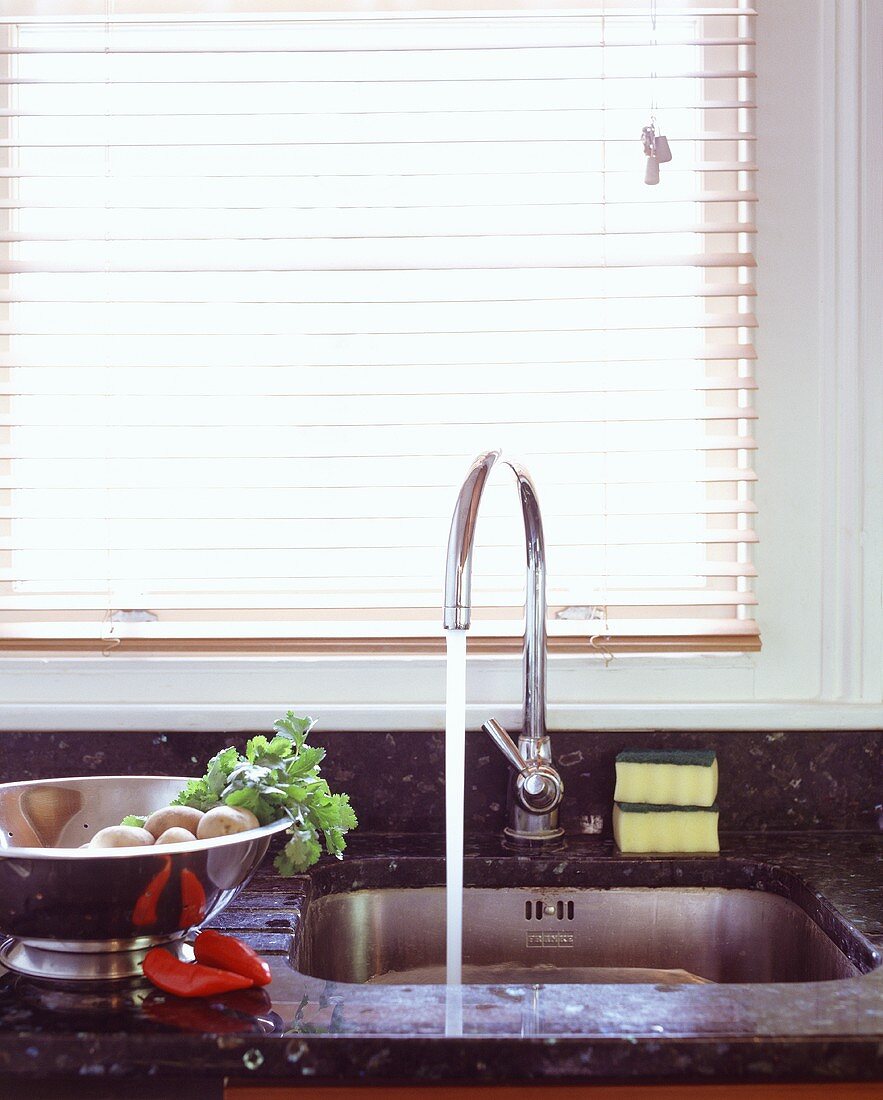 Fliessender Wasserhahn am Spülbecken in einer Küche