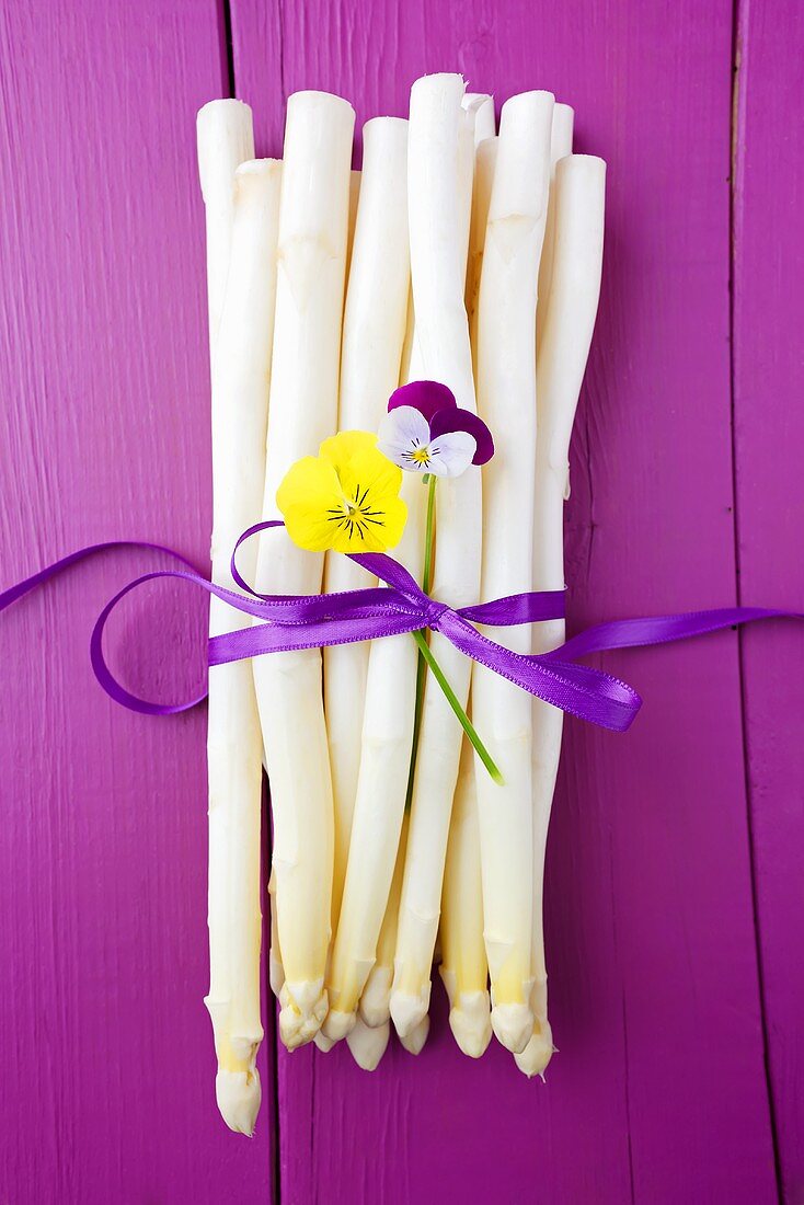A bunch of white asparagus on a purple wooden surface