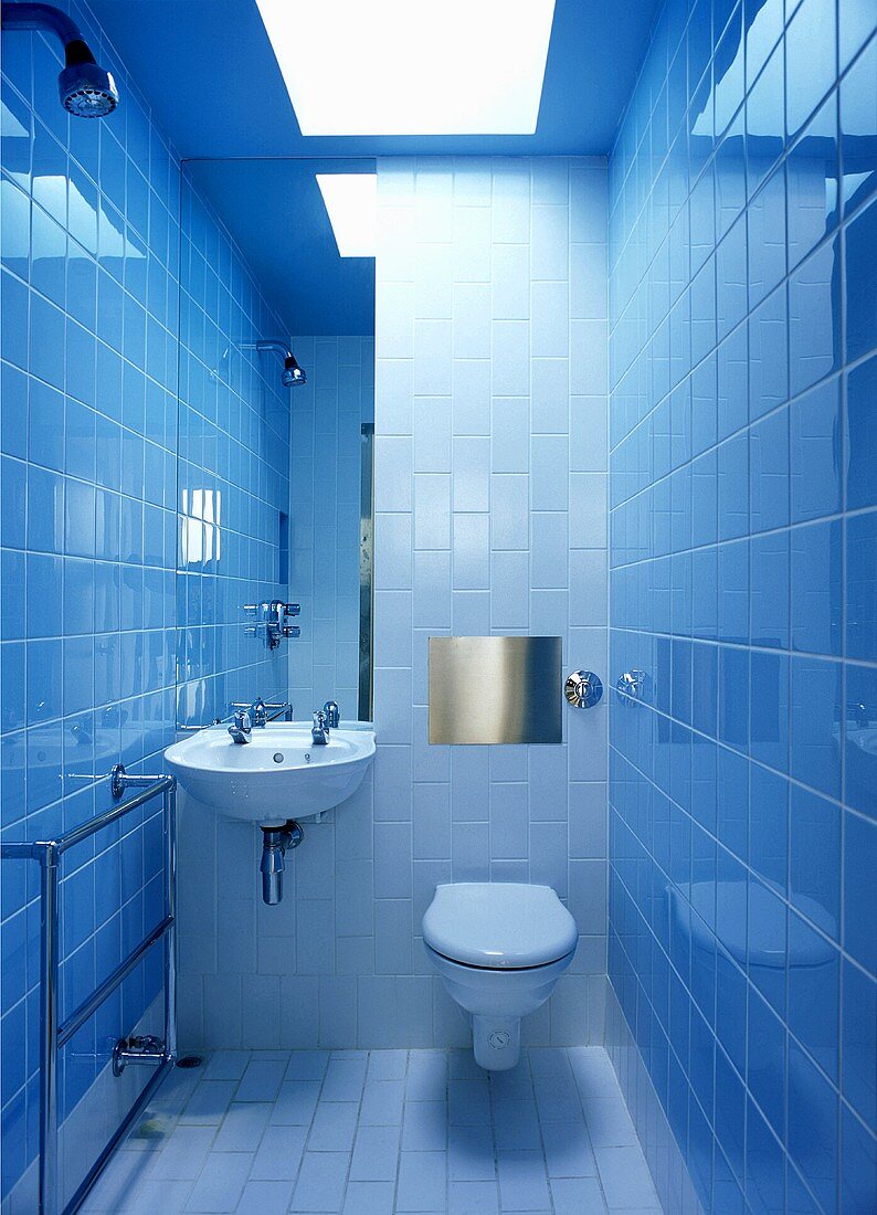 Modernes gefliestes Bad mit WC und Waschbecken und eingelassenem Lichtfeld in Decke