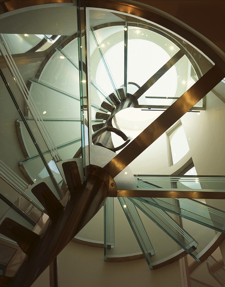 The underneath a spiral staircase with glass stairs and a steel frame