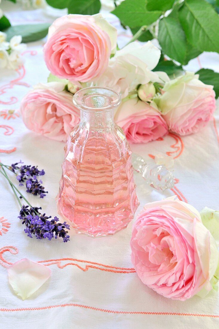 Rose oil, pink roses and lavender flowers